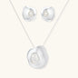 Organic curved earrings and necklace featuring baroque pearls in eco-zinc alloy settings on neutral background