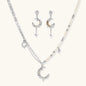Mixed-metal jewelry set featuring layered necklaces with crescent moon pendant and pearl beads, plus matching star-drop earrings.