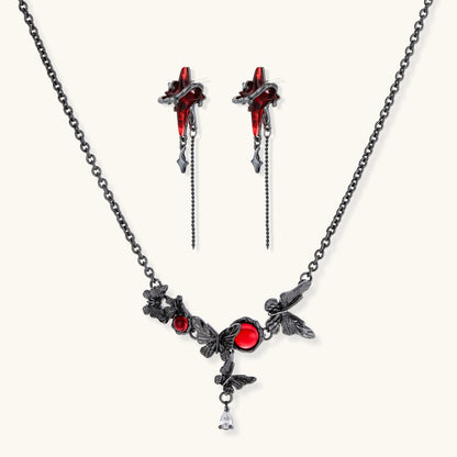 Gothic jewelry set with red resin cross pendants wrapped in dark metal chains on cream background.
